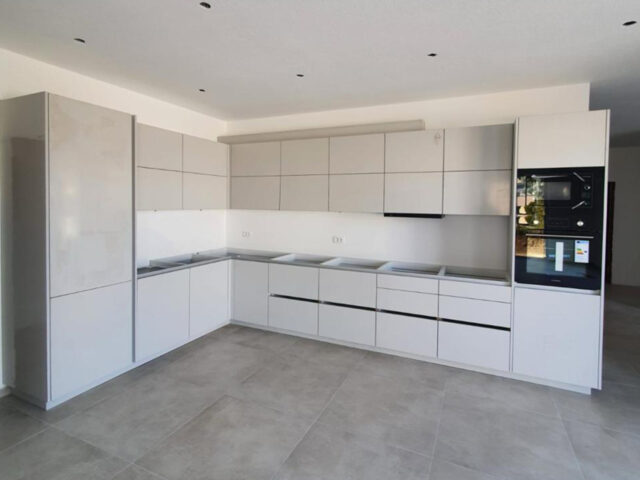 Moderne weisse Küche nach Mass in L-Form mit klaren Linien und integrierten Geräten