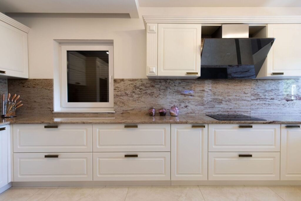 Klassische Küche nach Mass mit weissen Fronten und Naturstein Arbeitsplatte