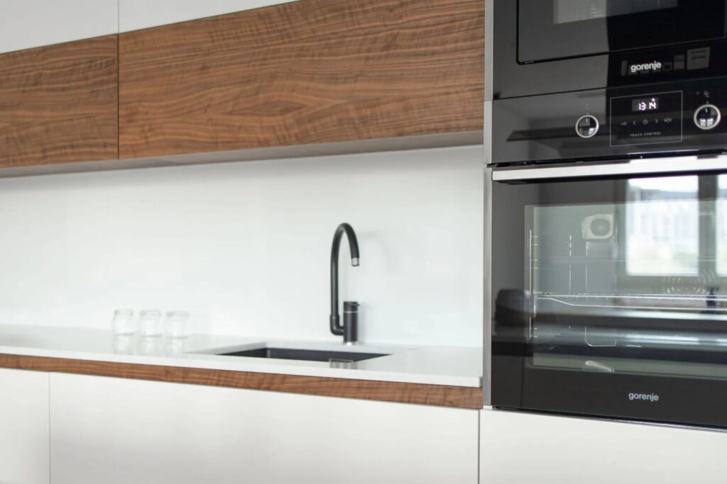 Detail einer Küche nach Mass mit Spüle, Holzarbeitsfläche und integrierten Geräten