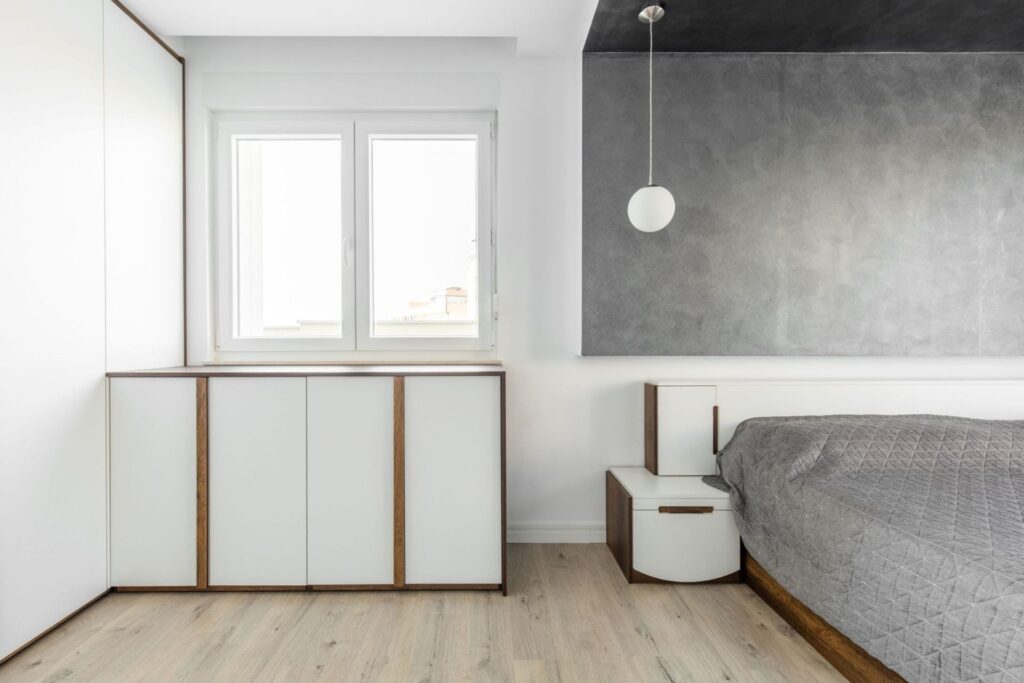 Individuelle Einbauschranklösung nach Mass mit integriertem Stauraum neben Fenster in modernem Raum